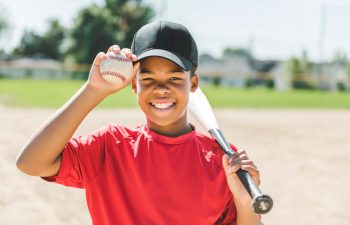 Happy Afro-American boy with a baseball bat and ball