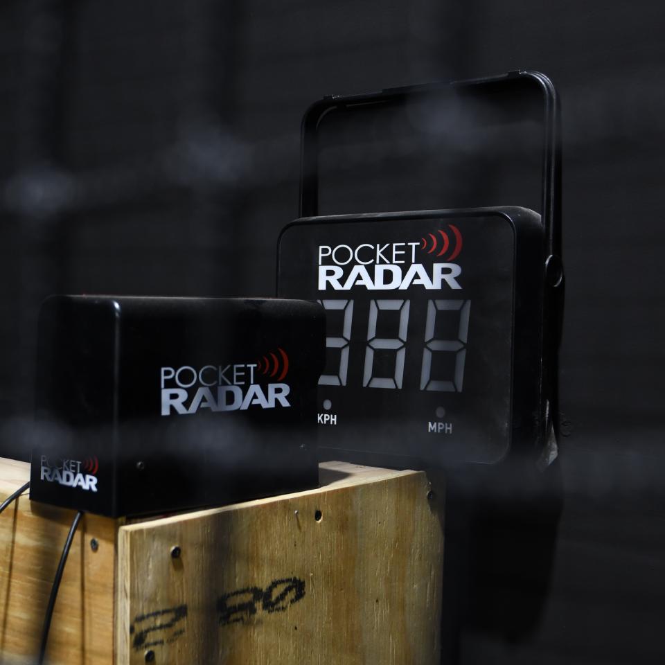 Digital speed radar display and sensor device labeled "Pocket Radar" mounted on a wooden box, showing a speed reading of 38.8 MPH.