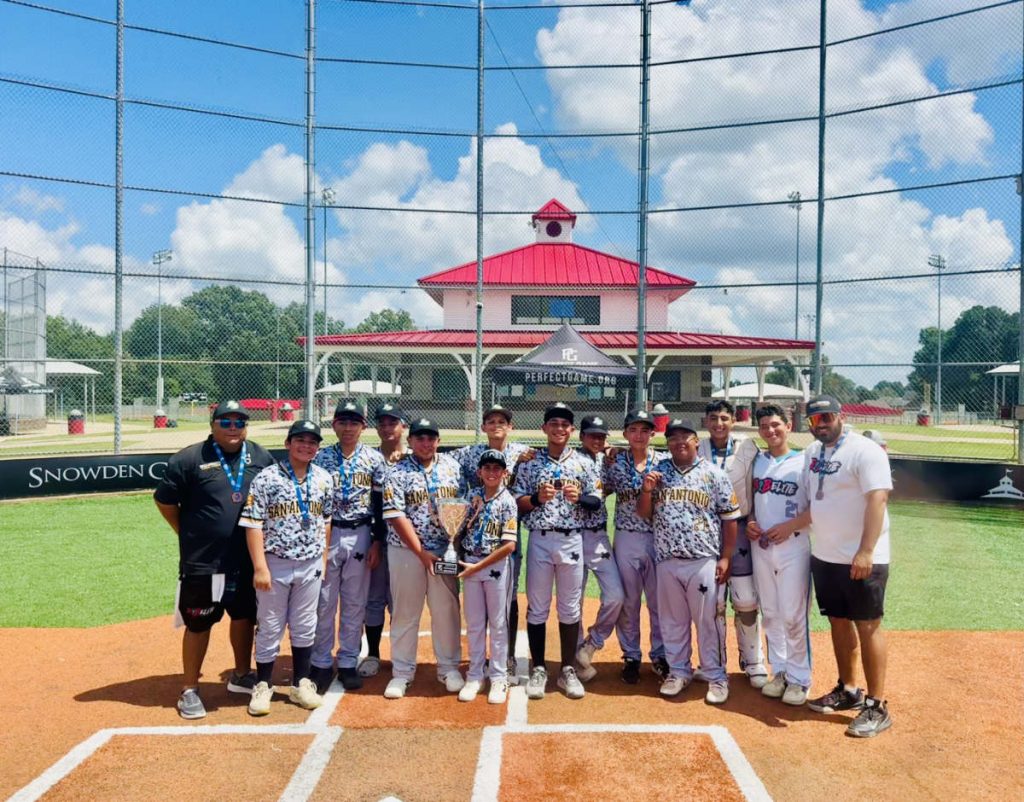 Youth baseball team posing with trophy and medals on field at Snowden Grove complex, wearing camo-print San Antonio jerseys.
