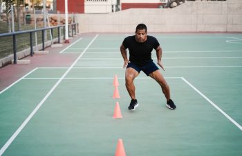 Hispanic man doing speed and agility cone drills workout session outdoors - Focus on man face